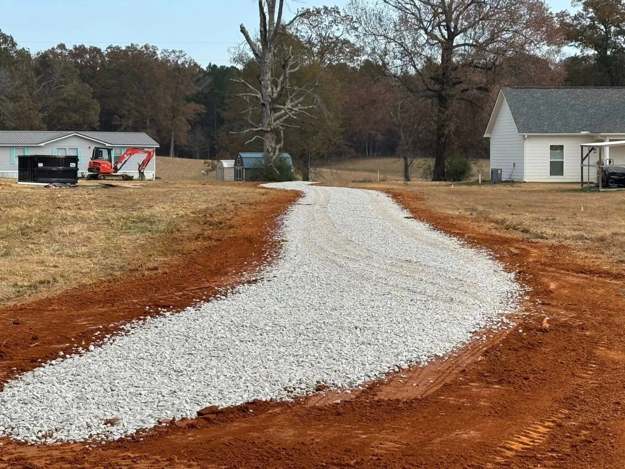 new gravel driveway installation with excavation equipment on site in rural mississippi.